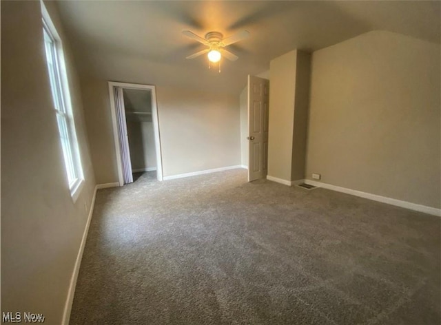 spare room featuring dark carpet, ceiling fan, and lofted ceiling