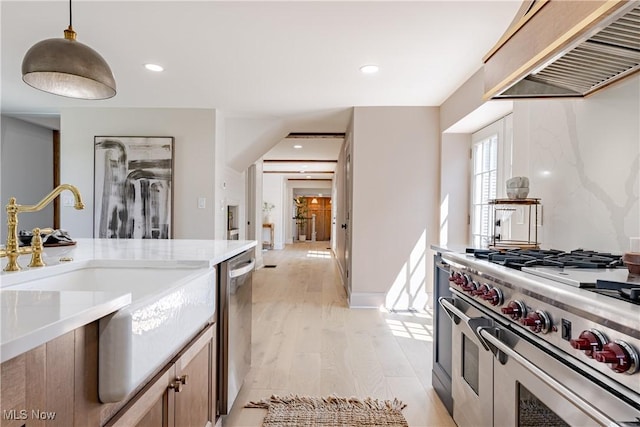 kitchen featuring pendant lighting, sink, light hardwood / wood-style flooring, appliances with stainless steel finishes, and extractor fan