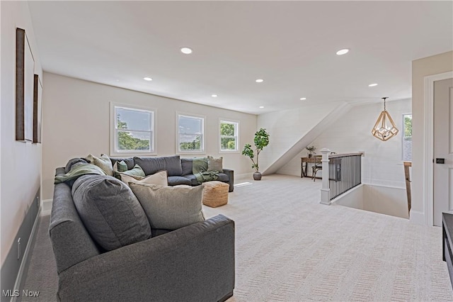 carpeted living room with an inviting chandelier