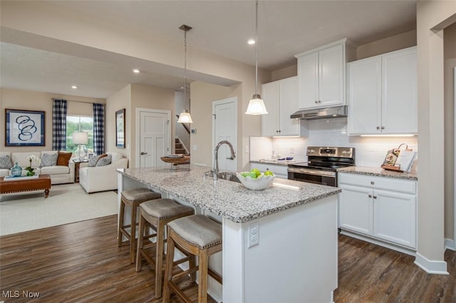 kitchen with decorative light fixtures, white cabinetry, stainless steel electric range oven, and a kitchen island with sink