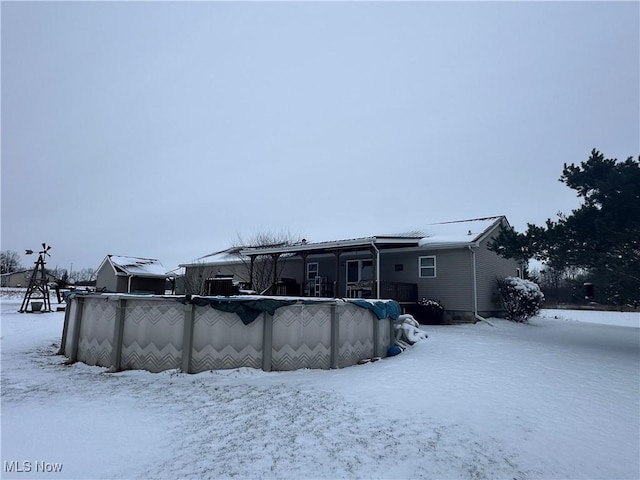 snow covered rear of property with a covered pool