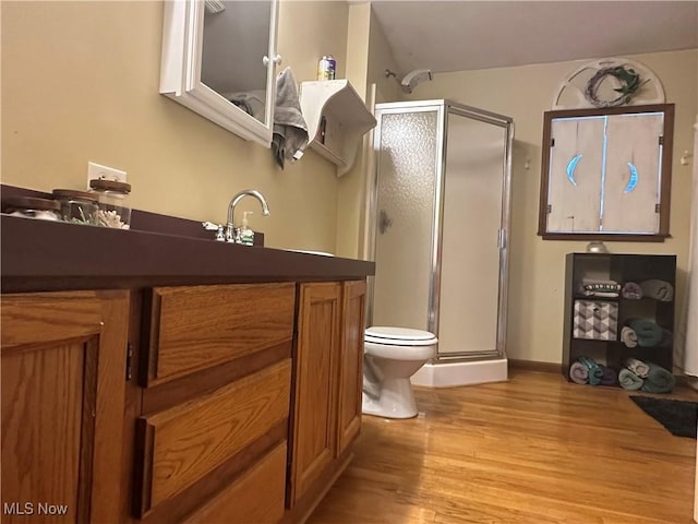 bathroom with hardwood / wood-style floors, vanity, toilet, and a shower with door