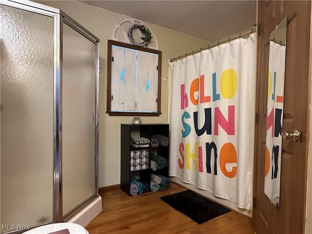 bathroom with toilet, wood-type flooring, and walk in shower