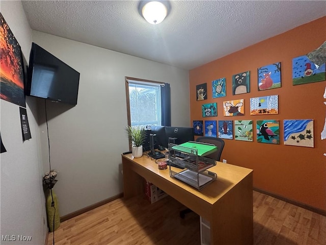 home office with wood-type flooring and a textured ceiling