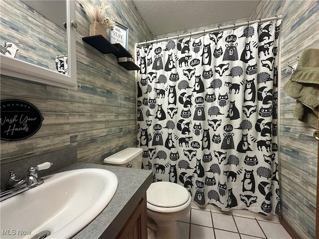 bathroom featuring tile patterned floors, wooden walls, vanity, and a textured ceiling