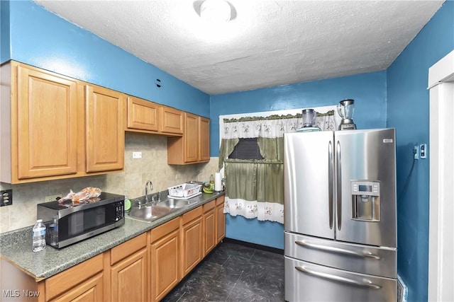 kitchen with a textured ceiling, backsplash, sink, and appliances with stainless steel finishes