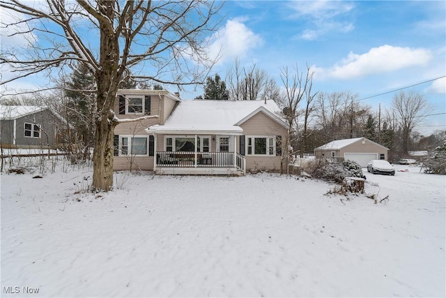 snow covered house featuring an outbuilding and a garage