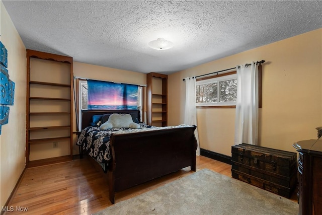 bedroom with a textured ceiling and light hardwood / wood-style floors