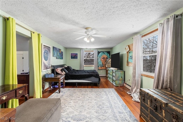 bedroom with ceiling fan, a baseboard radiator, a textured ceiling, and hardwood / wood-style flooring