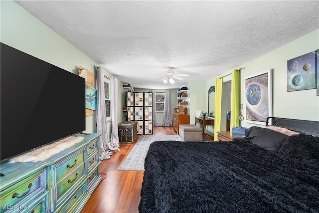 bedroom with ceiling fan, light hardwood / wood-style floors, and a textured ceiling