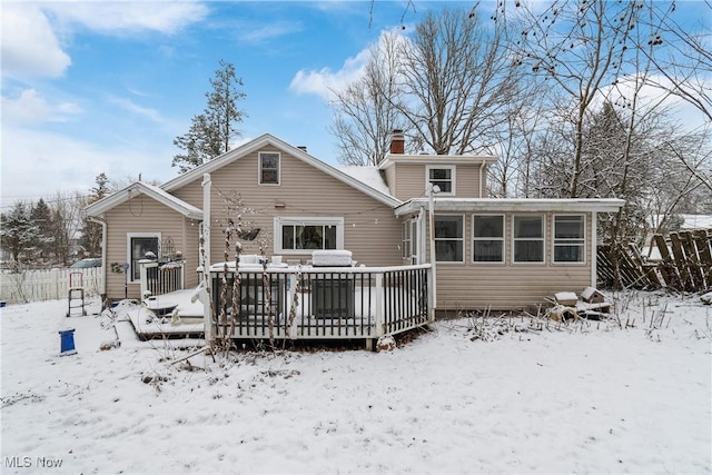 snow covered house with a sunroom and a deck