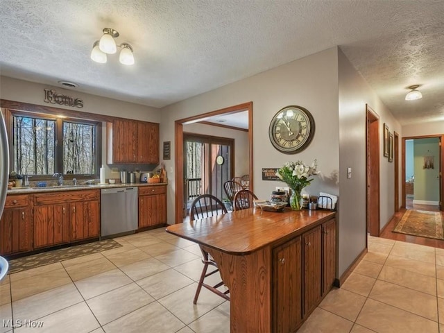 kitchen with a textured ceiling, light tile patterned flooring, dishwasher, and sink