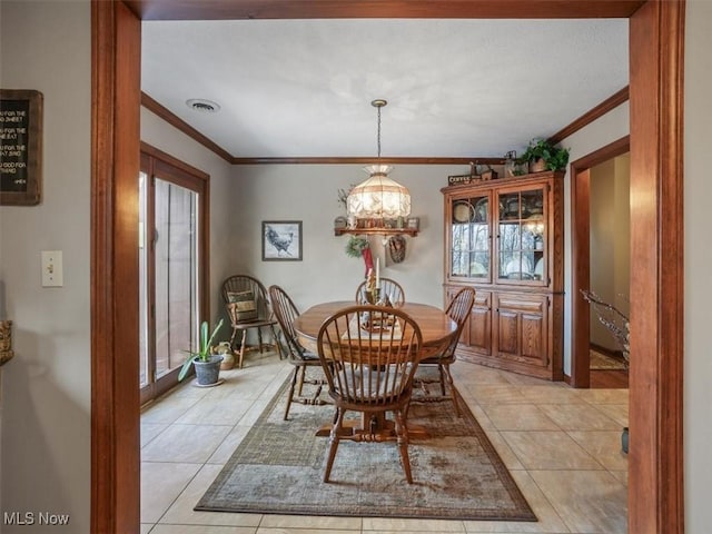 dining area featuring an inviting chandelier, crown molding, and light tile patterned floors