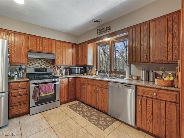 kitchen with appliances with stainless steel finishes, light tile patterned floors, sink, range hood, and tasteful backsplash