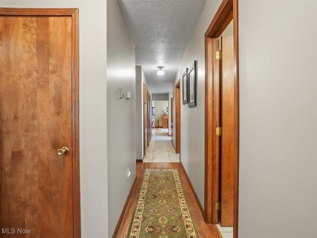 hall featuring a textured ceiling and light tile patterned floors