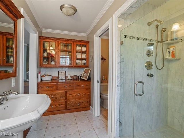 bathroom featuring sink, toilet, tile patterned floors, a shower with door, and crown molding