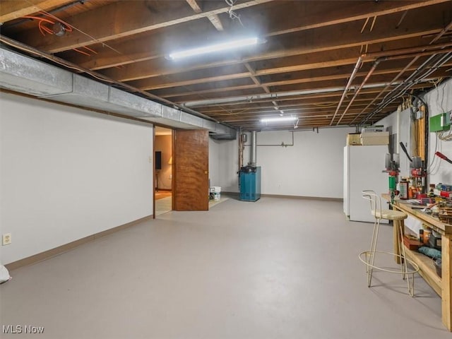 basement with white fridge, a workshop area, and water heater