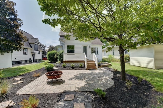 back of property featuring a wooden deck, a patio area, a yard, and a fire pit