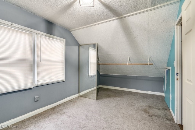 unfurnished bedroom with carpet, a textured ceiling, and lofted ceiling