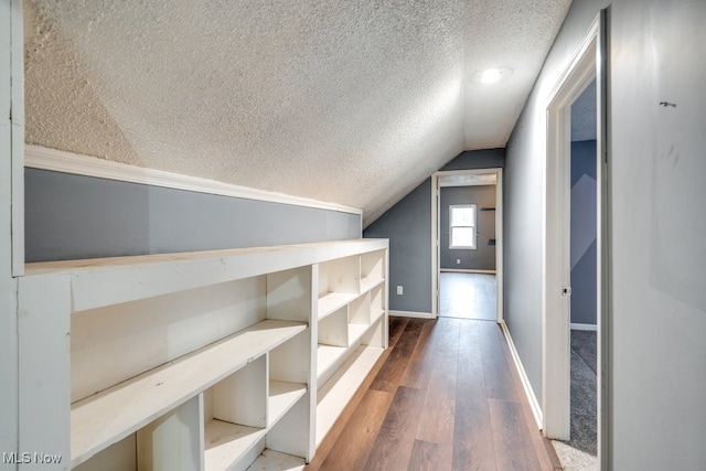 interior space featuring a textured ceiling, dark wood-type flooring, and lofted ceiling