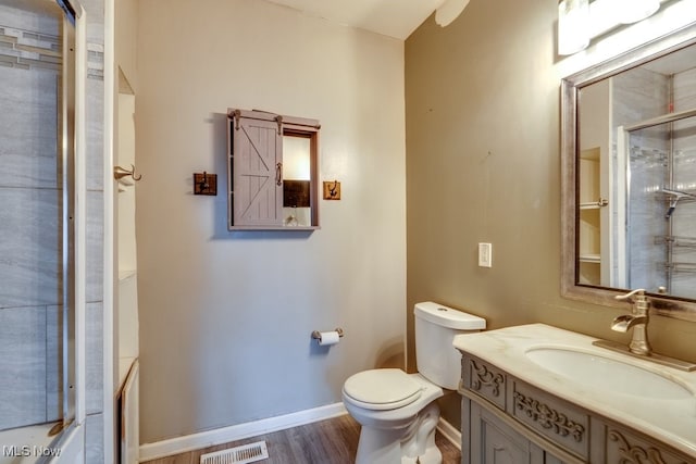 full bathroom with hardwood / wood-style floors, vanity, enclosed tub / shower combo, and toilet