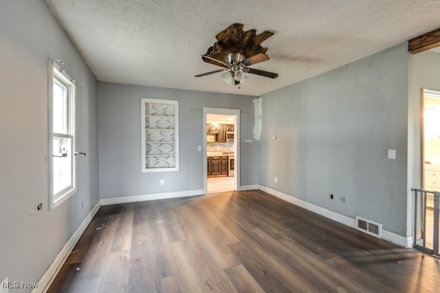 spare room with a textured ceiling, dark hardwood / wood-style floors, and ceiling fan