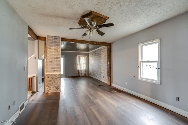 spare room with beamed ceiling, ceiling fan, dark hardwood / wood-style flooring, and a textured ceiling