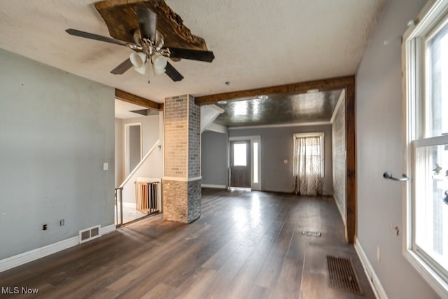 unfurnished living room featuring decorative columns, ceiling fan, beamed ceiling, and dark hardwood / wood-style floors