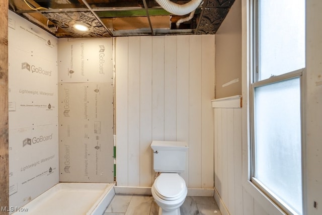 bathroom featuring wood walls and toilet