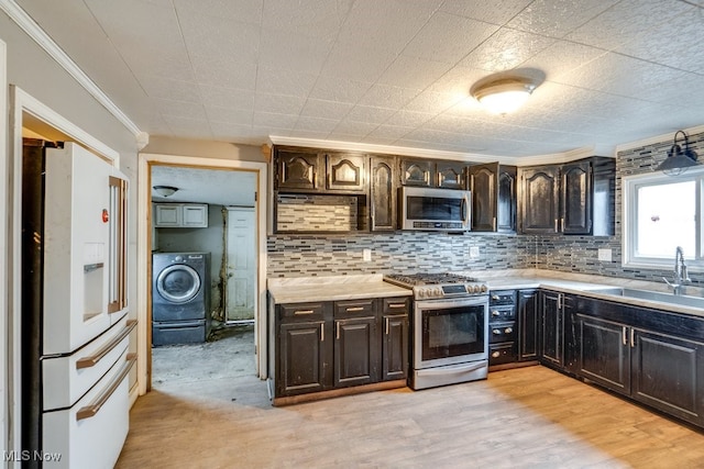 kitchen with dark brown cabinetry, sink, light hardwood / wood-style flooring, washer / dryer, and appliances with stainless steel finishes