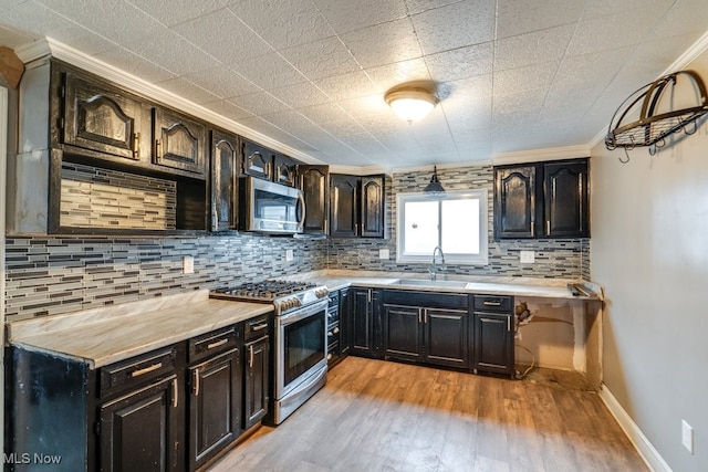 kitchen featuring sink, stainless steel appliances, light hardwood / wood-style flooring, decorative backsplash, and ornamental molding