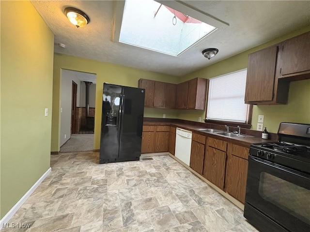 kitchen with a textured ceiling, sink, a skylight, and black appliances