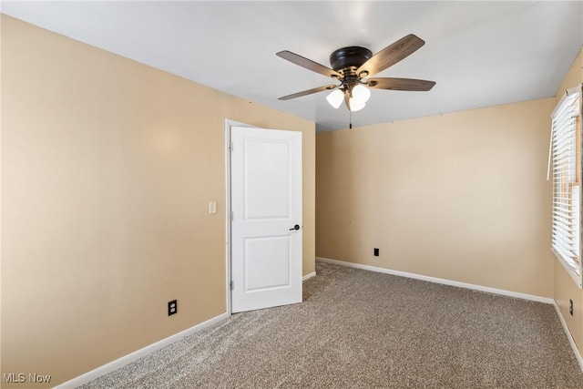 carpeted spare room featuring a wealth of natural light and ceiling fan