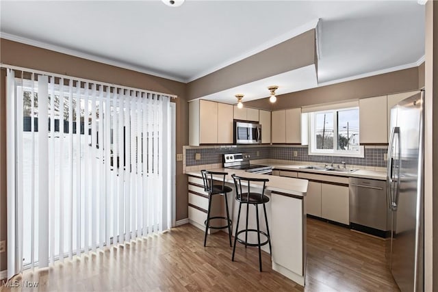 kitchen with dark wood-type flooring, a kitchen breakfast bar, sink, kitchen peninsula, and stainless steel appliances