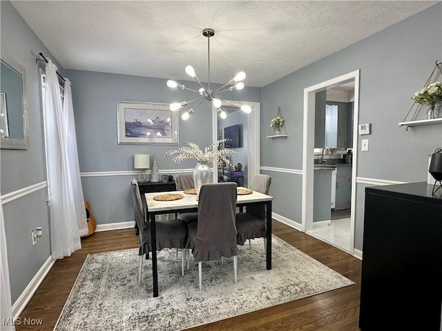 dining space featuring sink, a notable chandelier, dark hardwood / wood-style flooring, and a textured ceiling