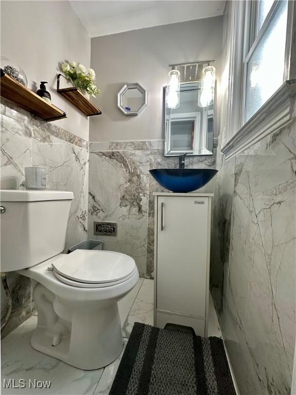 bathroom featuring vanity, toilet, and tile walls