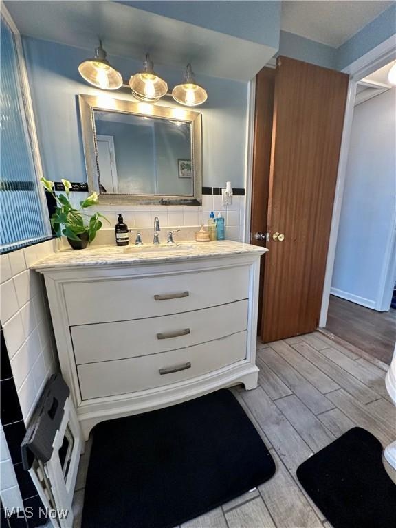 bathroom with hardwood / wood-style floors, vanity, and tile walls