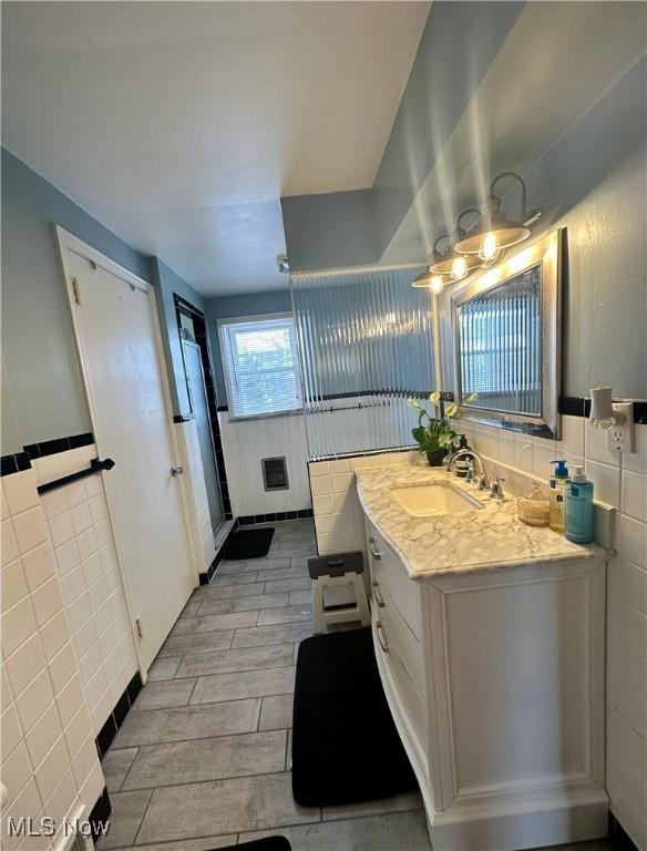 bathroom with vanity and tile walls