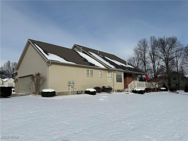 snow covered house featuring a garage and a wooden deck