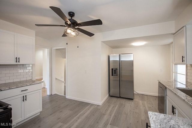 kitchen with white cabinets, decorative backsplash, light stone counters, and appliances with stainless steel finishes