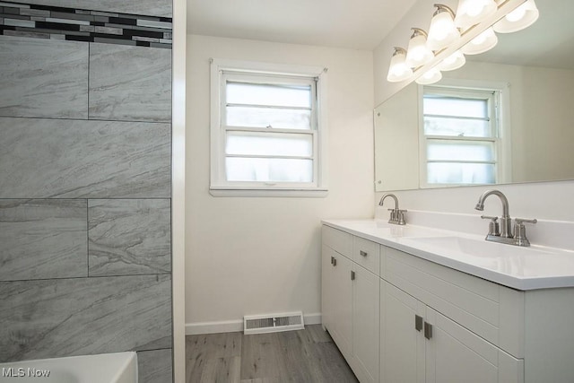 bathroom with hardwood / wood-style flooring, vanity, and a bath