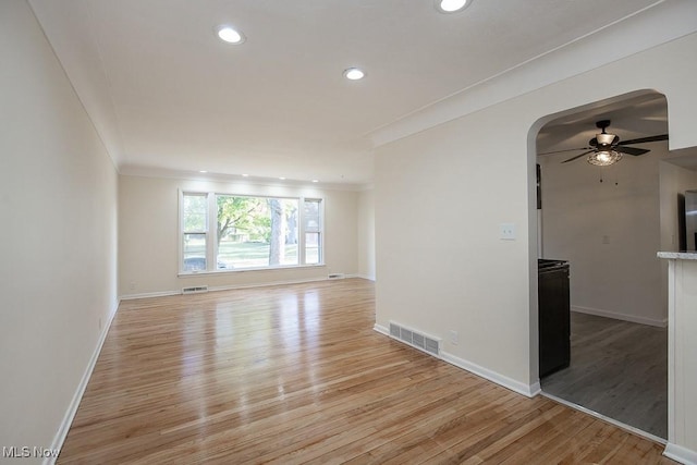 empty room featuring ceiling fan, light wood-type flooring, and ornamental molding