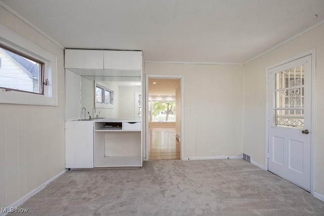 interior space featuring white cabinets, sink, light colored carpet, and crown molding