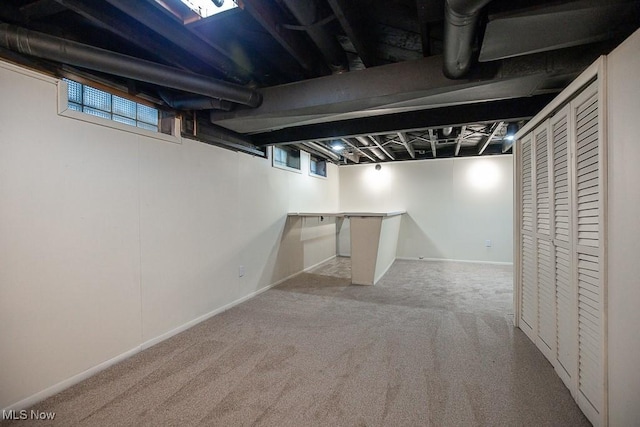 basement with a wealth of natural light and light carpet