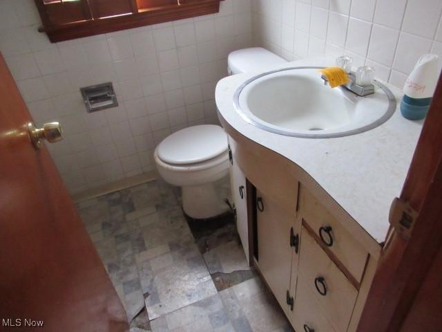 bathroom with backsplash, vanity, toilet, and tile walls