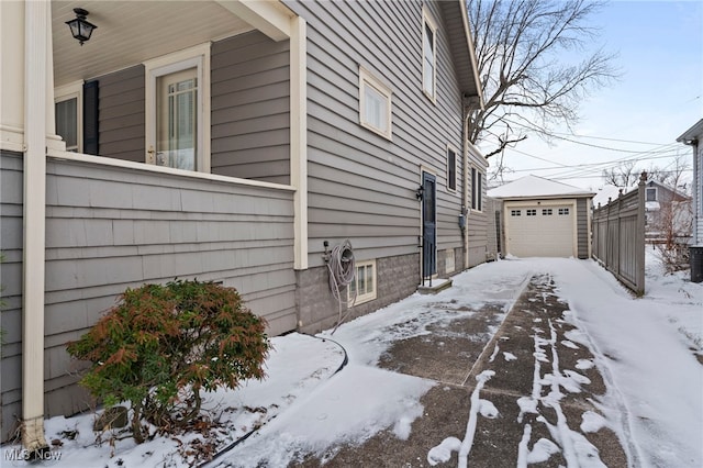 view of snow covered exterior with a garage and an outdoor structure