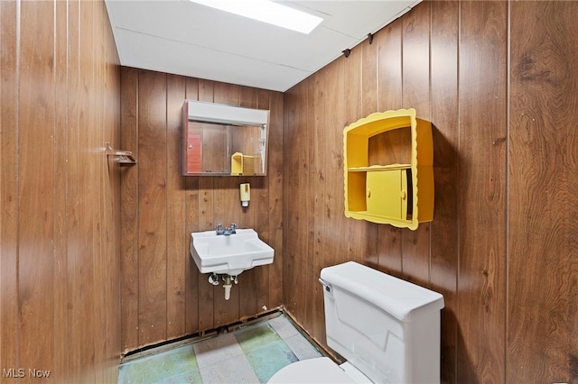 bathroom featuring sink, toilet, and wood walls