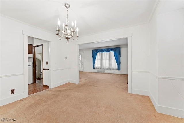 empty room featuring carpet, washer / dryer, crown molding, and an inviting chandelier