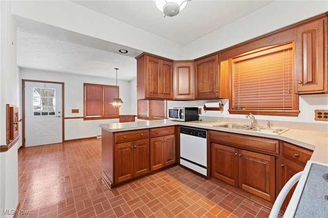 kitchen featuring kitchen peninsula, sink, pendant lighting, dishwasher, and range