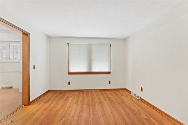 empty room with light hardwood / wood-style flooring and a textured ceiling